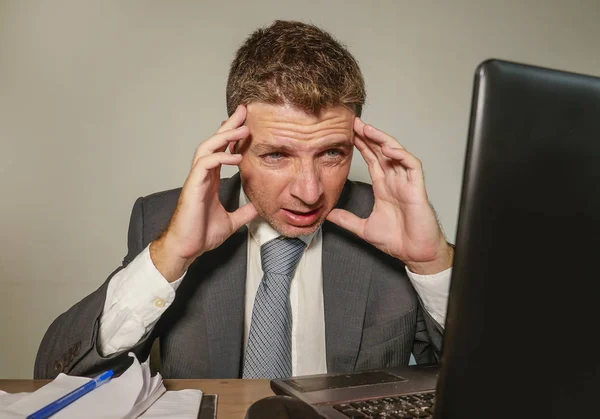 若いイライラしてストレスのビジネス スーツの男し 頭痛と片頭痛の企業の仕事の問題で病気を感じて苦しんでいるオフィスのラップトップ コンピューターのデスクで圧倒される作業のネクタイ — ストック写真