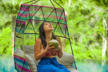 hamak içme Hindistan cevizi suyu rahatlatıcı resort havuz tropikal adada lüks tatil zevk, asılı oturan genç mutlu ve çekici Asyalı Çinli kadın
