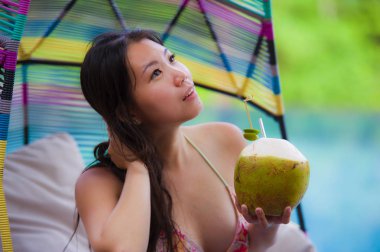 hamak içme Hindistan cevizi suyu rahatlatıcı resort havuz tropikal adada lüks tatil zevk, asılı oturan genç mutlu ve çekici Asyalı Çinli kadın