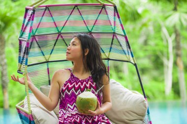 hamak içme Hindistan cevizi suyu rahatlatıcı resort havuz tropikal adada lüks tatil zevk, asılı oturan genç mutlu ve çekici Asyalı Çinli kadın