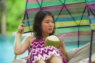 hamak içme Hindistan cevizi suyu rahatlatıcı resort havuz tropikal adada lüks tatil zevk, asılı yalan genç mutlu ve çekici Asyalı Çinli kadın