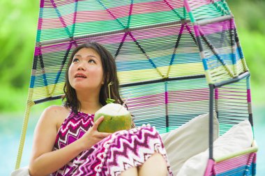 hamak içme Hindistan cevizi suyu rahatlatıcı resort havuz tropikal adada lüks tatil zevk, asılı yalan genç mutlu ve çekici Asyalı Koreli kadın