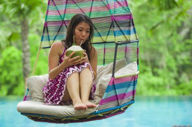 hamak içme Hindistan cevizi suyu rahatlatıcı resort havuz tropikal adada lüks tatil zevk, asılı oturan genç mutlu ve çekici Asyalı Koreli kadın