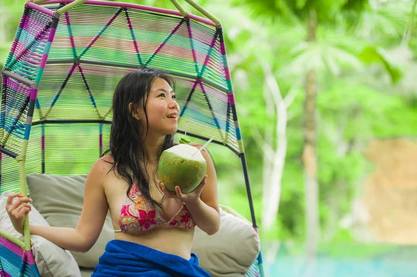 hamak içme Hindistan cevizi suyu rahatlatıcı resort havuz tropikal adada lüks tatil zevk, asılı oturan genç mutlu ve çekici Asyalı Çinli kadın