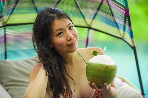 若い幸せと魅力的なアジア韓国女性 ハンギング ハンモックの熱帯の島で贅沢な休日を楽しむリゾートのスイミング プールでリラックスしたココナッツ水を飲んで座っています — ストック写真