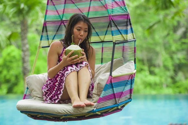 hamak içme Hindistan cevizi suyu rahatlatıcı resort havuz tropikal adada lüks tatil zevk, asılı oturan genç mutlu ve çekici Asyalı Koreli kadın
