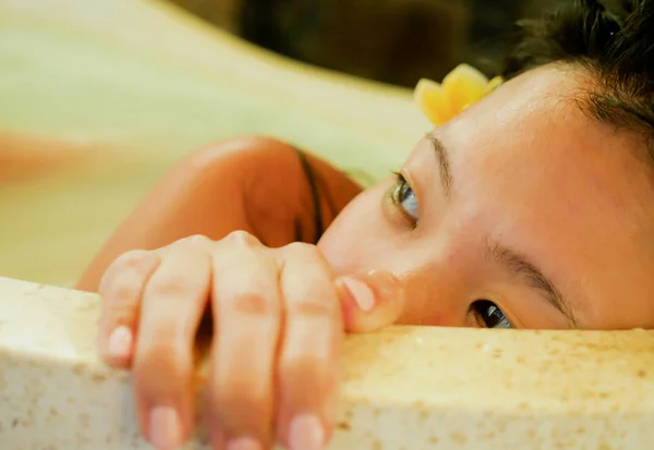 young beautiful and happy relaxed Asian Chinese woman enjoying indulging milk bath in bathtub at luxury Spa smiling delighted having skin beauty treatment in well being and healthy lifestyle