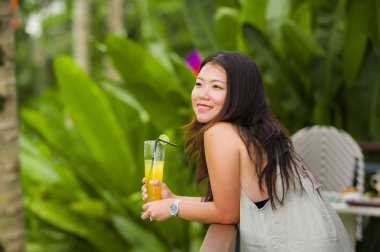 Genç güzel ve mutlu Asya tatil tatil tropikal pirinç teras gülümseyen içinde kadının sağlıklı portakal suyu içme memnun Kore açık havada samimi portre yaşam tarzı