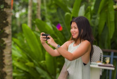 yaşam tarzı açık havada dikey genç güzel ve mutlu Asya Çin backpacker kadının tatil tropikal pirinç teras memnun gülümsüyor, cep telefonu ile manzara fotoğrafı çekmek