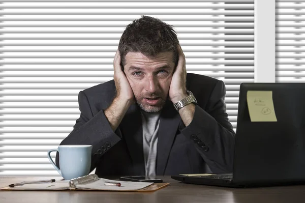 young attractive depressed and frustrated man working at office computer desk desperate and overwhelmed with financial business problem feeling upset suffering depression and anxiety crisis