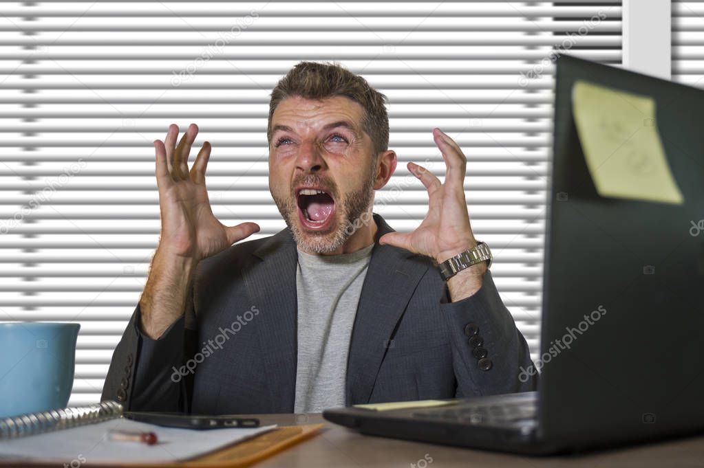 young attractive depressed and frustrated man working at office computer desk desperate and overwhelmed with financial business problem feeling upset suffering depression and anxiety crisis 