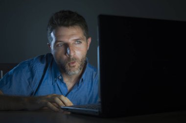 young aroused and excited sex addict man watching porn mobile online in laptop computer light night at home desk in pornography addiction and internet pornographic content concept clipart