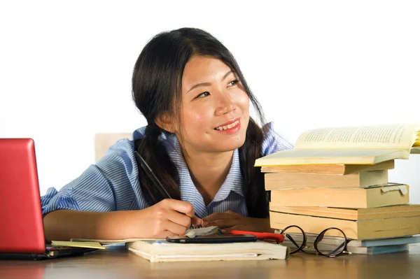 young happy and cute Asian Chinese teenager student smiling happy working and studying with texbooks and laptop computer sitting on desk isolated on white background in education success