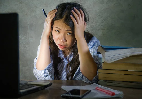 若いを強調したし 不満のアジア韓国学生の女の子を圧倒し 疲れを感じの机の上のパソコンと本杭と頑張って疲れし に心配して分離した背景 — ストック写真