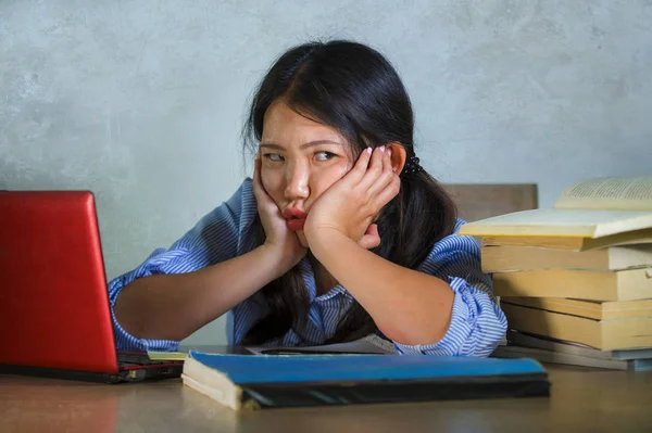 若いを強調したし 不満のアジア韓国学生の女の子を圧倒し 疲れを感じの机の上のパソコンと本杭と頑張って疲れし に心配して分離した背景 — ストック写真