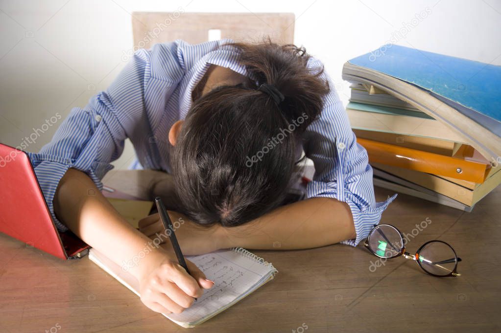 young depressed and stressed student girl working with laptop and book pile overwhelmed and frustrated preparing exam feeling lazy and tired in education problem and academic frustration