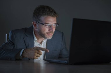 ticaret forex piyasası veya koyu arka plan üzerinde izole verileri analiz mali iş dizüstü bilgisayar kullanan gece geç saatlerde çalışan genç çekici ve adanmış işkolik girişimci adam