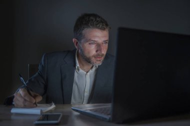 ticaret forex piyasası veya koyu arka plan üzerinde izole verileri analiz mali iş dizüstü bilgisayar kullanan gece geç saatlerde çalışan genç çekici ve adanmış işkolik girişimci adam