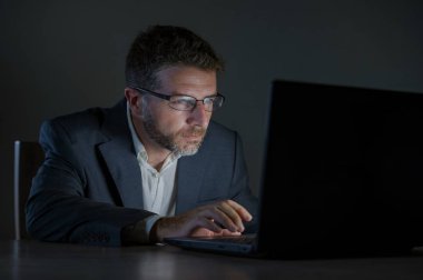 ticaret forex piyasası veya koyu arka plan üzerinde izole verileri analiz mali iş dizüstü bilgisayar kullanan gece geç saatlerde çalışan genç çekici ve adanmış işkolik girişimci adam