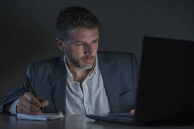 ticaret forex piyasası veya koyu arka plan üzerinde izole verileri analiz mali iş dizüstü bilgisayar kullanan gece geç saatlerde çalışan genç çekici ve adanmış işkolik girişimci adam