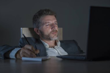 ticaret forex piyasası veya koyu arka plan üzerinde izole verileri analiz mali iş dizüstü bilgisayar kullanan gece geç saatlerde çalışan genç çekici ve adanmış işkolik girişimci adam