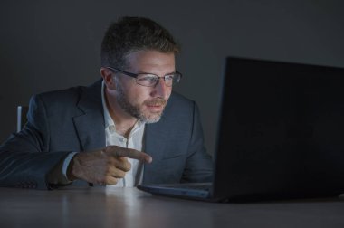 ticaret forex piyasası veya koyu arka plan üzerinde izole verileri analiz mali iş dizüstü bilgisayar kullanan gece geç saatlerde çalışan genç çekici ve adanmış işkolik girişimci adam