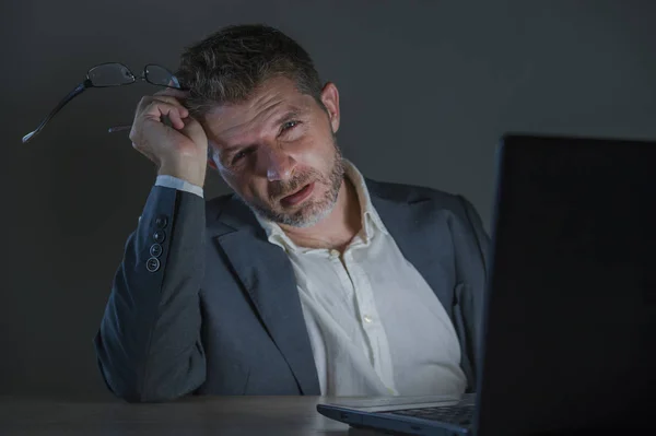 young attractive wasted and tired entrepreneur man working late night at office laptop computer desk exhausted and sleepy in financial business problem and overworked employee concept