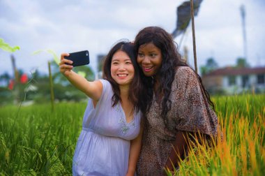 karışık etnik köken Asyalı Koreli kız ve siyah Afro Amerikalı kadın, selfie cep telefonunuzla birlikte izole kız alarak geleneksel köy alan zevk egzotik tropik tatil pirinç