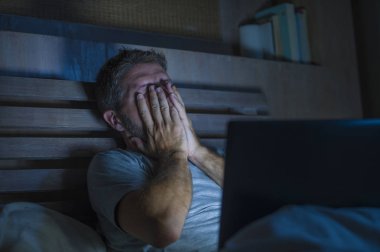 yatakta duygu uykulu ve iş proje son tarih stres kavramı içinde çok çalışan dizüstü bilgisayar ile meşgul geç gece yorgun çalışma çekici yorgun ve stresli işkolik adam