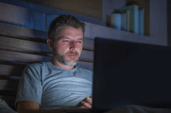 社会的なメディア中毒あるいはワーカホリック実業家の概念にラップトップ コンピューターが付いているベッドに夜遅く集中して魅力的で幸せなインターネット中毒の若者ネットワーク — ストック写真