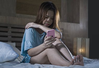 Genç depresif Asyalı Koreli kız cep telefonuyla yatakta gece duygu üzgün ve depresyonda kurbanı siber zorbalık veya kırık kalp umutsuz kadın ifadesinde depresyon acı ağlayan