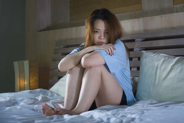 young beautiful and depressed Asian Chinese woman crying in bed at night having  depression problem and anxiety crisis feeling sad in girl suffering broken heart or cyber bullying concept