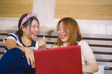 iki genç güzel ve mutlu Asya Kore öğrenci kızlara birlikte gülüyor dizüstü neşeli bilgisayar yatakta kadın dostluk içinde eğlenmek internet sosyal medya kullanarak ev yatak odası
