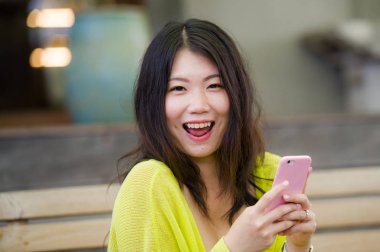 yaşam tarzı açık havada kentsel portre genç çekici ve güzel Asyalı Japon kadın cep telefonu tatlı ve neşeli internet sosyal medya app kullanarak zevk ifade yüz