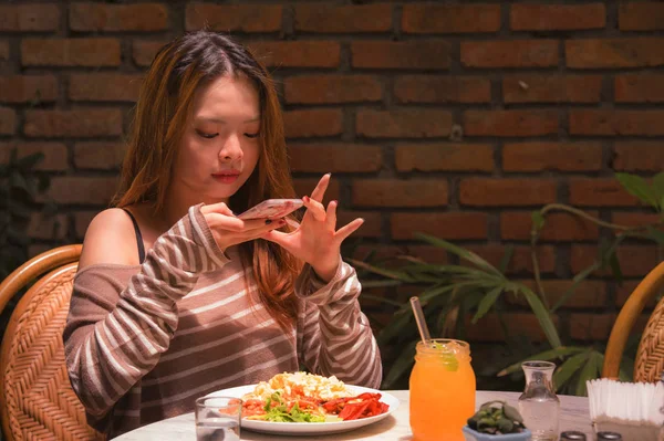 年轻漂亮快乐的亚洲中国学生女孩坐在甜咖啡店用手机相机在互联网社交媒体食品博客概念中拍摄她的饭菜照片的生活方式肖像 — 图库照片