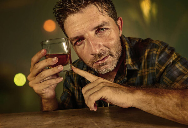 молодой грустный и подавленный алкоголик со стаканом виски, пьяный и пьяный, не сопротивляющийся выпивке в баре ночью впадает в алкогольную зависимость и проблему алкоголизма
 