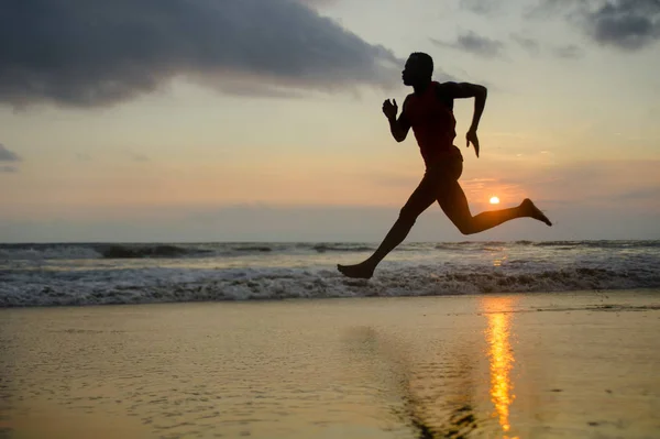 在日落海滩跑步的年轻有吸引力的适合运动和强壮的黑人非洲裔美国人的剪影在专业运动员和跑步者锻炼中努力训练海水和冲刺 — 图库照片