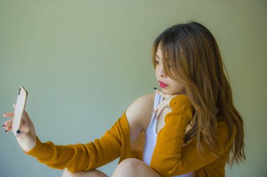 telefon kullanarak genç çekici ve rahat Asyalı Çinli kız telefon evde yatak zevk internet online video aramasında genç öğrenci yaşam tarzı kavramı yatakta oturup sosyal medya uygulaması