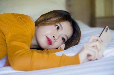 telefon kullanarak genç çekici ve rahat Asyalı Koreli kız telefon evde yatak keyfi internet online dating uygulaması veya genç öğrenci yaşam tarzı kavramı yatakta yatan sosyal medya