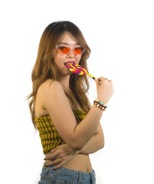 Genç mutlu ve seksi Asyalı kız serin moda güneş gözlüğü yaramaz neşeli alay poz lolipop şeker yemek beyaz arka plan üzerinde izole Korece portresi