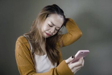 kırık kalp ve umutsuz holding cep telefonu ilişki acı duygu genç Şirin ve üzgün Asyalı Koreli kız ayrılmak koyu arka plan üzerinde izole Internet mesaj yoluyla kızlarından