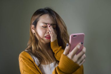 kırık kalp ve umutsuz holding cep telefonu ilişki acı duygu genç Şirin ve üzgün Asyalı Koreli kız ayrılmak koyu arka plan üzerinde izole Internet mesaj yoluyla kızlarından