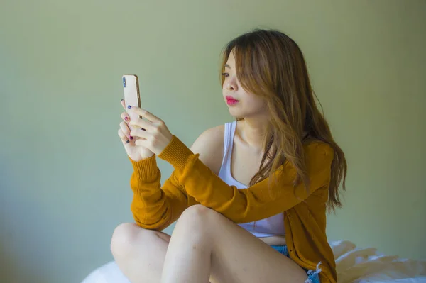 魅力的でリラックスしたアジア韓国少女使用して 携帯電話自宅インターネット オンライン ビデオ通話ではベッドルーム楽しんで 代学生ライフ スタイル コンセプトでベッドの上に座っているソーシャル メディア アプリで — ストック写真