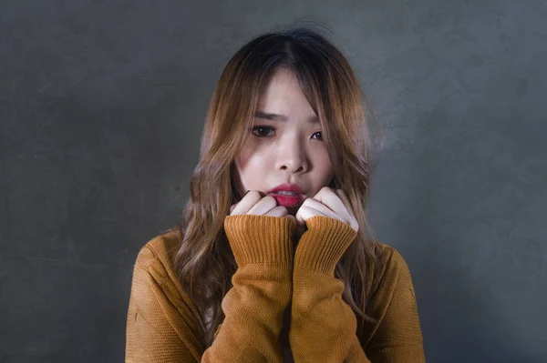 young crazy desperate and sad Asian Korean woman looking depressed and helpless feeling anguish and pain on isolated dark background in pain face expression suffering depression