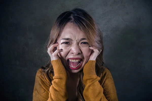 年轻疯狂绝望和不安的亚洲韩国女人尖叫着害怕和焦虑的感觉愤怒和痛苦隔离在黑暗的背景下戏剧性的痛苦脸表达在抑郁的概念 — 图库照片