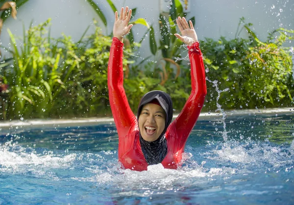 su geleneksel İslam'ın başörtüsü ve tatil gezi zevk İslam mayo giyen resort yüzme havuzu sıçramasına ve sahip eğlenceli heyecan ile oynayan genç mutlu ve neşeli Müslüman kadın