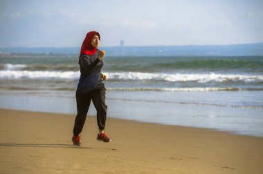 çalışan ve geleneksel Arap spor kıyafetlerle fitness egzersiz ve kilo kaybı kavramında sahilde koşu Islam türban Başörtüsü Müslüman kadında genç sağlıklı ve aktif atlet