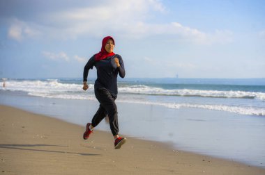 çalışan ve geleneksel Arap spor kıyafetlerle fitness egzersiz ve kilo kaybı kavramında sahilde koşu Islam türban Başörtüsü Müslüman kadında genç sağlıklı ve aktif atlet
