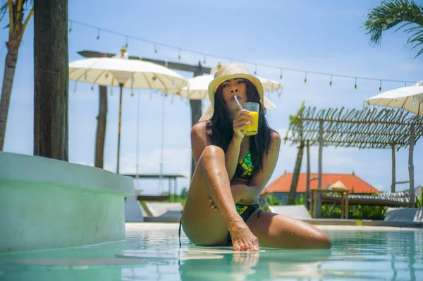 若いですセクシーと魅力的なエキゾチックなアジアの女性でビキニと夏の帽子飲みジュースでパラダイススイミングプールリゾートバー笑顔幸せな熱帯島での豪華な休日の旅行を楽しんで — ストック写真