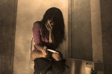 Genç, korkmuş ve çaresiz hamile bir kadın ya da genç bir kız tuvalette oturup istenmeyen hamilelik ve planlanmamış annelik yüzünden ağlayan öngörü testinin pozitif sonuçlarını kontrol ediyor. 